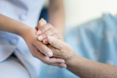 Eine Pflegekraft hält die Hand eines Patienten